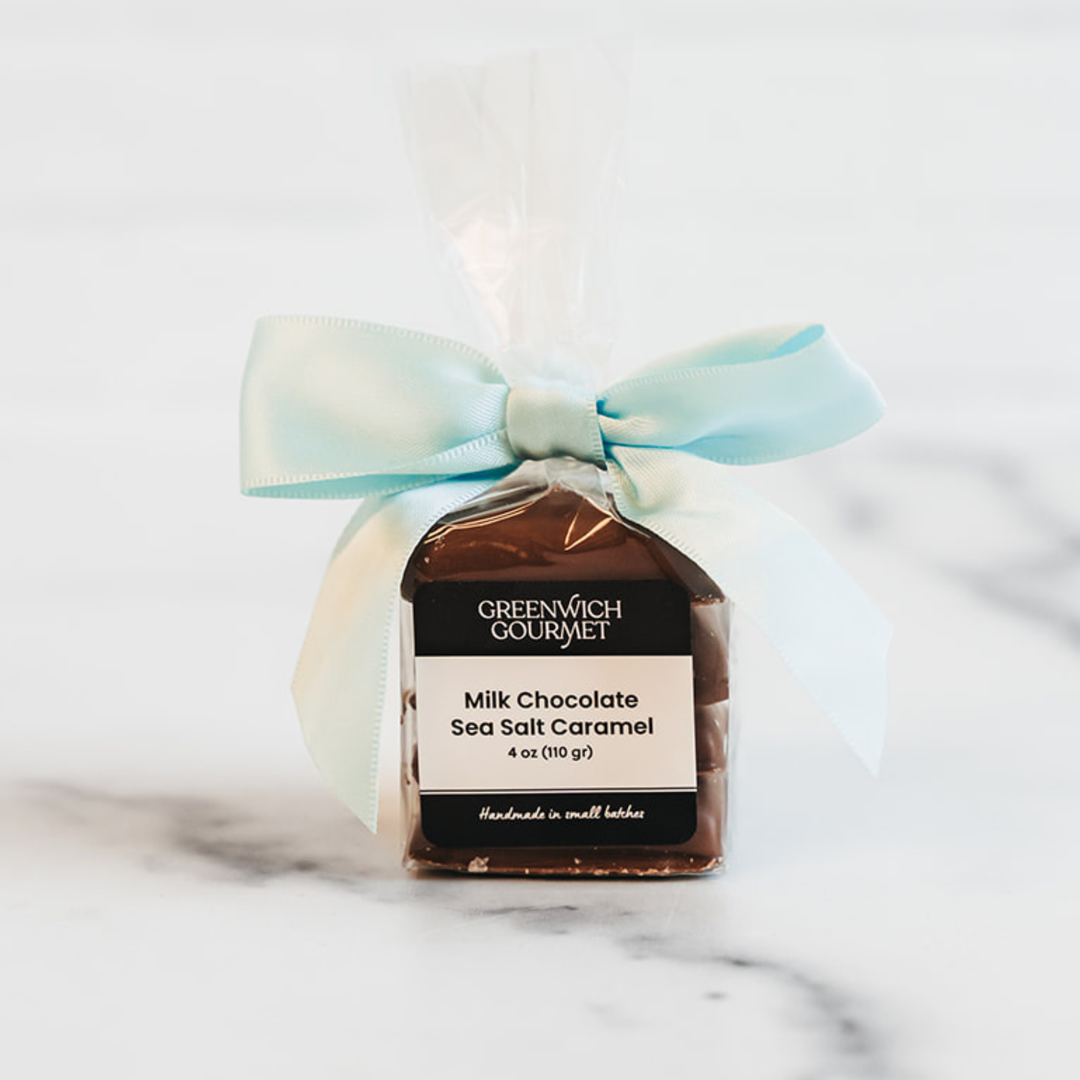 Greenwich Gourmet milk chocolate sea salt caramel package with a light blue ribbon on a marble surface.