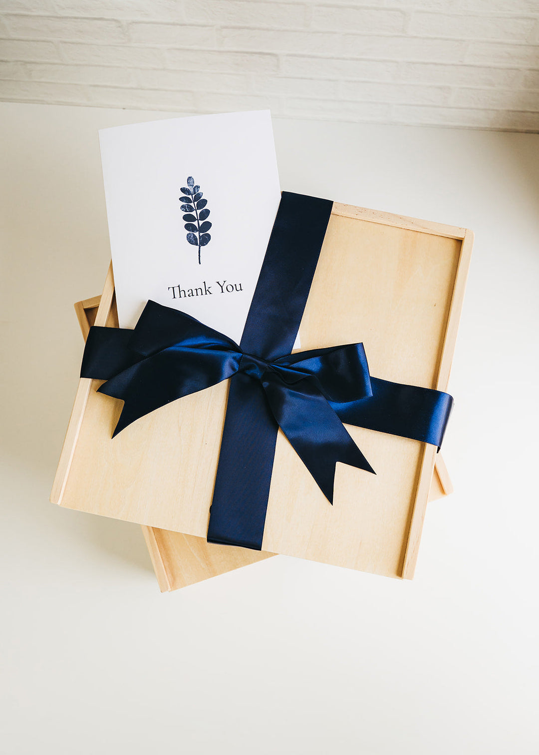 Overhead view of a Giften Market wooden gift crate tied with a navy satin bow