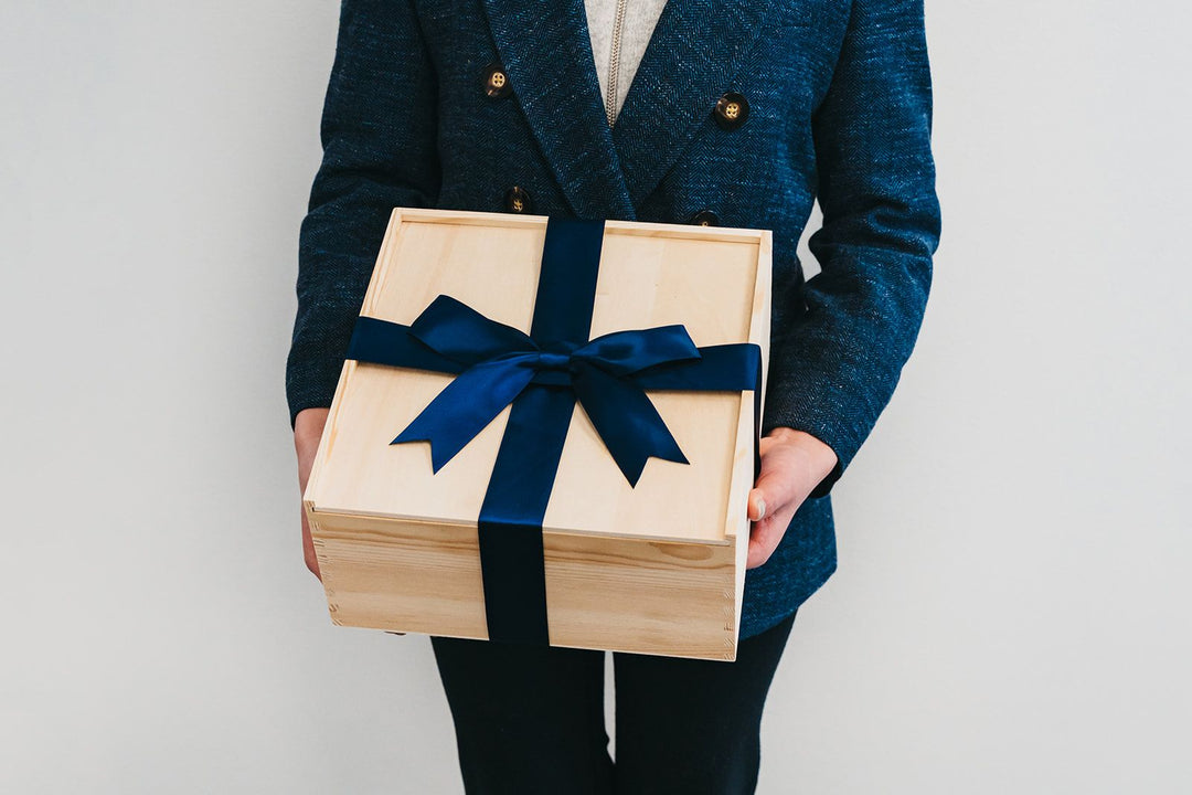 A natural wood gift box tied with a navy satin ribbon, the signature Giften Market presentation for corporate client gifts.