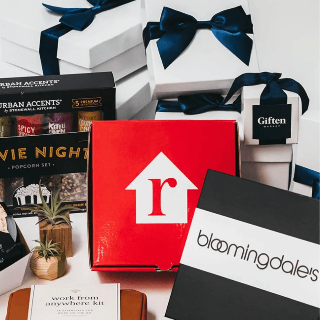 Assorted premium gift boxes with navy ribbons, branded packaging, snacks, and small plants
