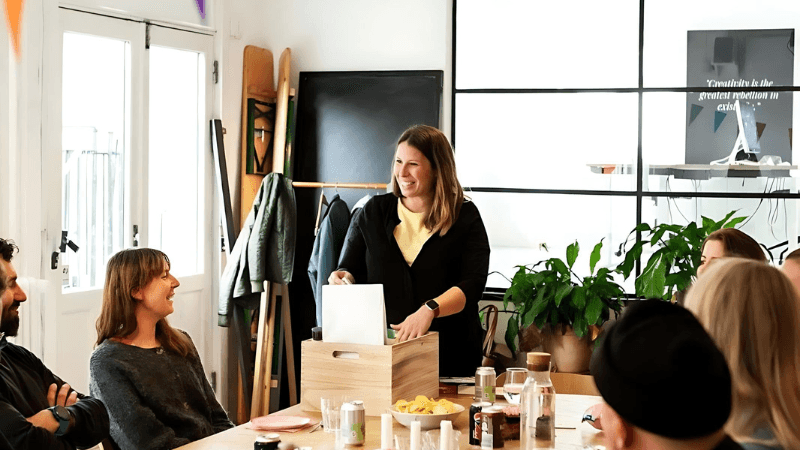 Employee opening a wooden gift box at an office table with snacks and drinks