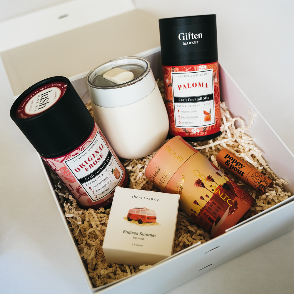 White gift box with cocktail mixes, tumbler, bar soap, lip balm, and gourmet gummies