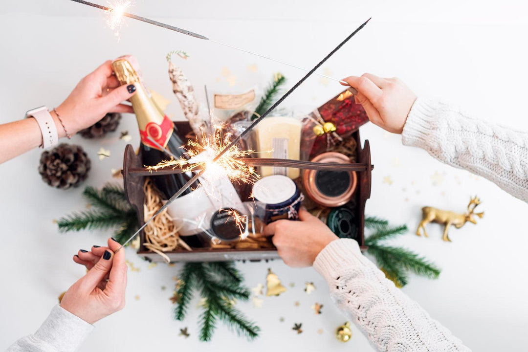 Festive wooden gift box with champagne, snacks, candle, and sparklers on holiday table