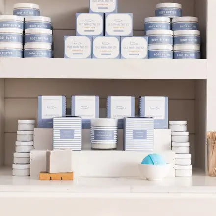 Curated gift display featuring bath bombs, body butters, soap bars, and candles in white packaging.