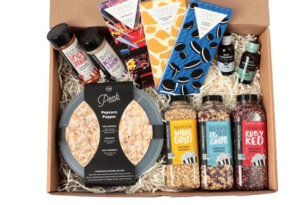 Movie night gift box with popcorn popper, gourmet popcorn kernels, snacks, sauces, and chocolate bars