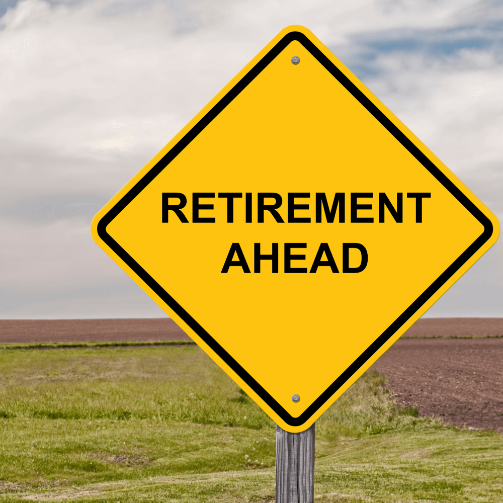 Yellow road sign reading 'Retirement Ahead' in a rural outdoor setting
