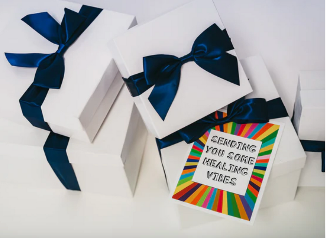 White gift boxes with navy blue ribbon and colorful get well soon card