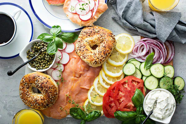 Gourmet bagel brunch board with smoked salmon, everything bagels, fresh vegetables, and cream cheese.