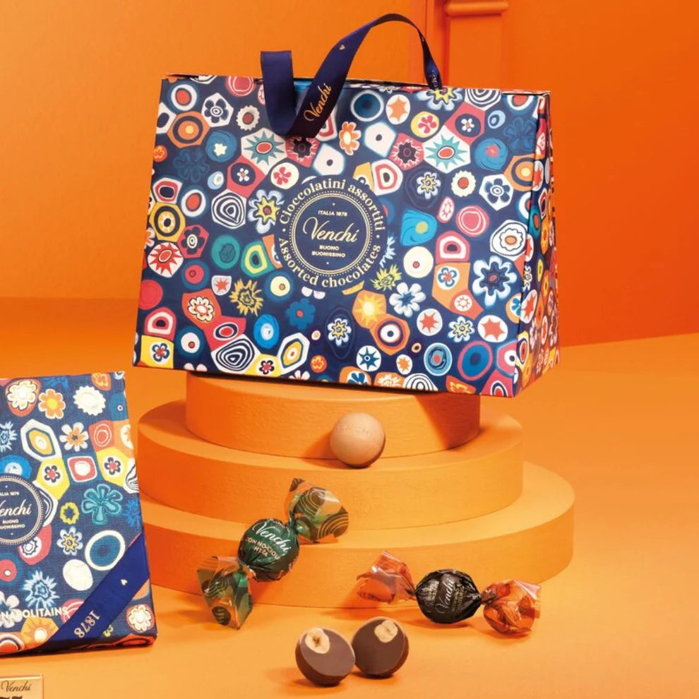 Colorful gift bag with assorted wrapped chocolates and truffles on orange display