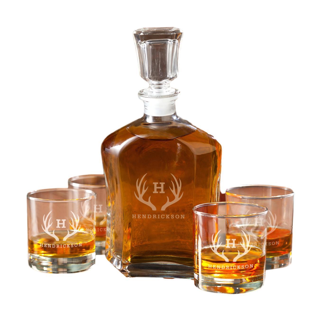 Glass decanter and four whiskey glasses with etched antler monogram design, filled with whiskey