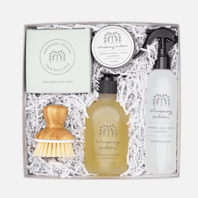 Gift box with natural hand soap, linen spray, dish soap, wooden brush, and salve on paper shreds