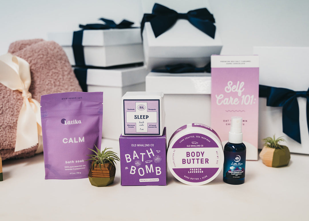 Lavender self-care gift box with bath soak, bath bomb, body butter, towel, and ribbon packaging