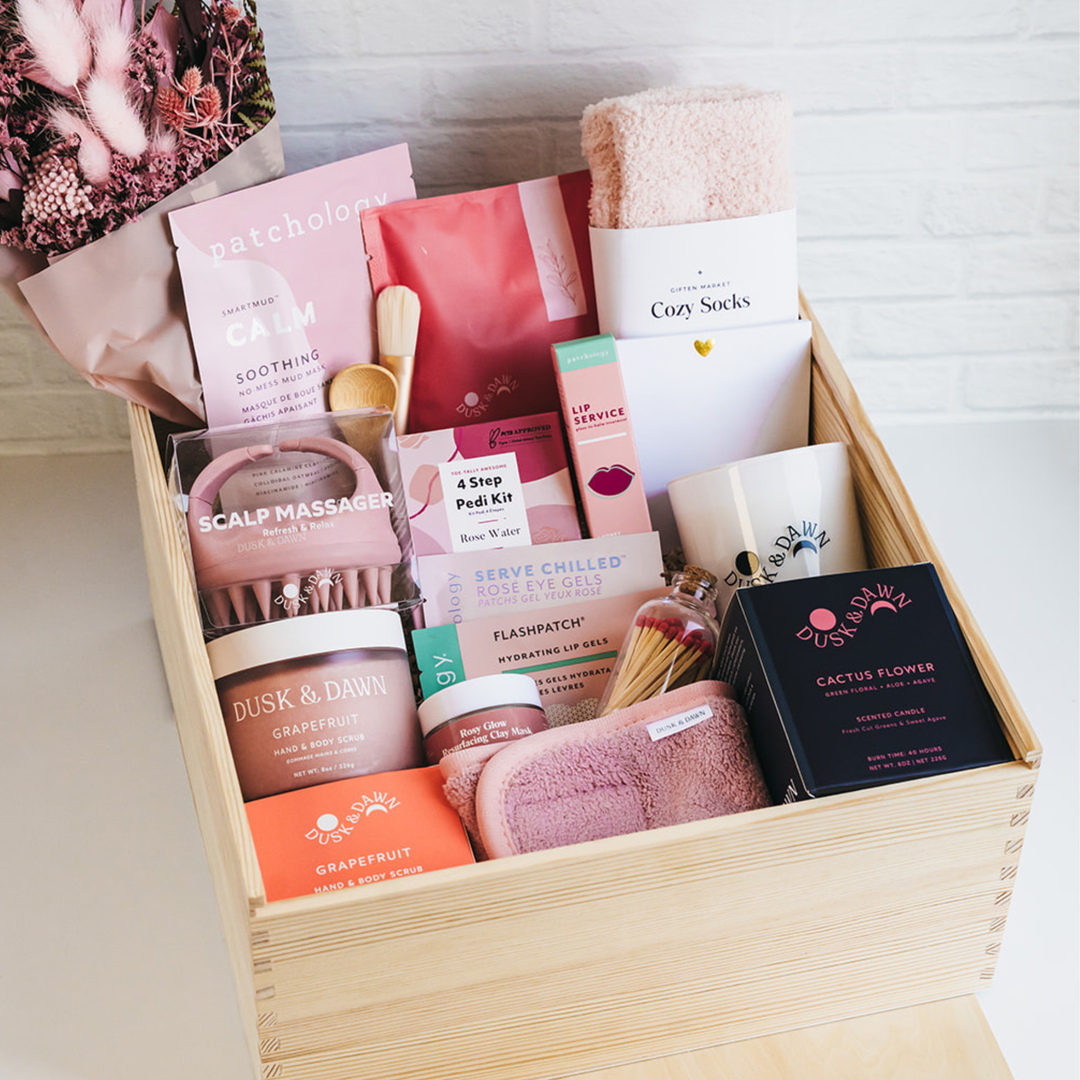 Luxury spa gift box with candle, cozy socks, snacks, skincare, and beauty essentials in wooden crate