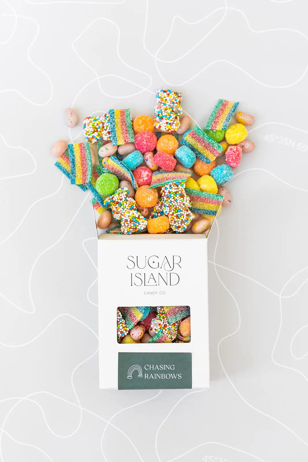 Open Chasing Rainbows box with rainbow sour strips and gummies spilling out the top