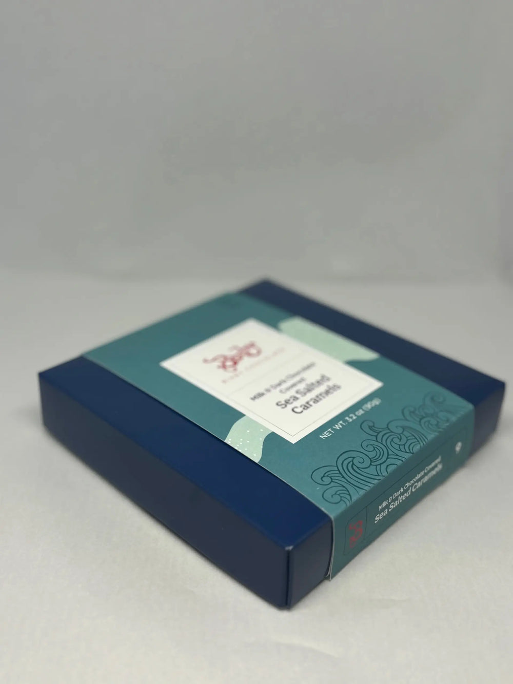 Closed blue Bixby sea salted caramels gift box with a teal sleeve, shown from above at an angle