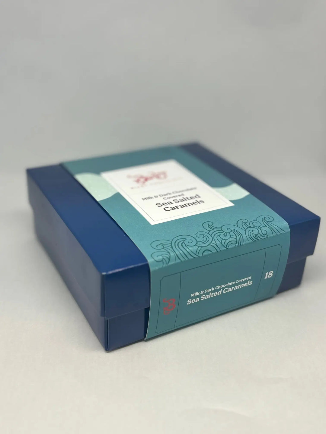 Blue Bixby caramels gift box with a teal sleeve, shown at an angle on a gray background