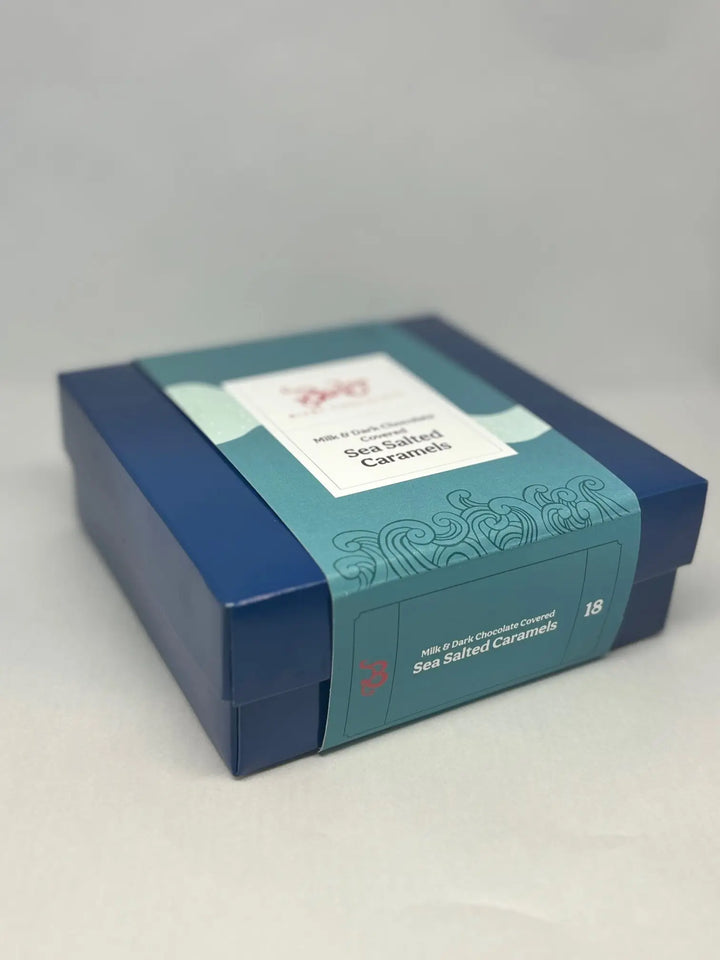 Blue Bixby caramels gift box with a teal sleeve, shown at an angle on a gray background
