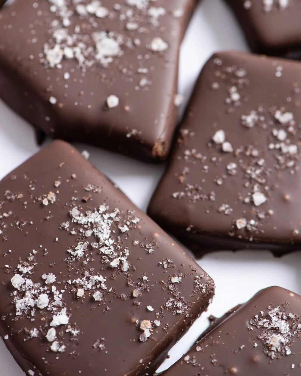 Close view of dark chocolate toffee pieces sprinkled with sea salt flakes