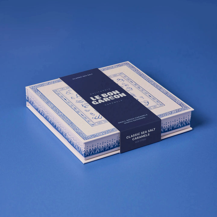 Le Bon Garcon Classic Sea Salt Caramels gift box in blue and white with a navy band, on a blue background