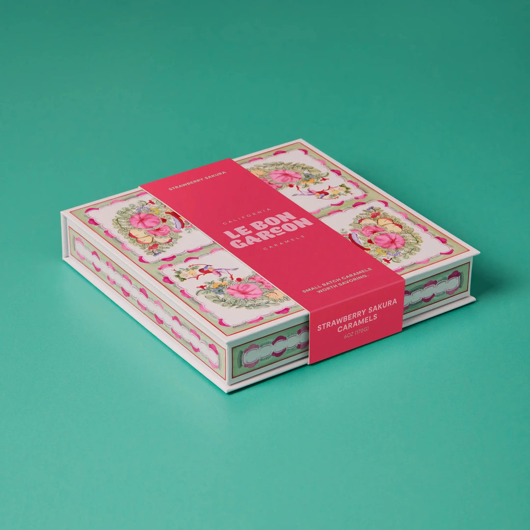 Le Bon Garcon Strawberry Sakura Caramels gift box in pink floral print with a pink band, on a teal background