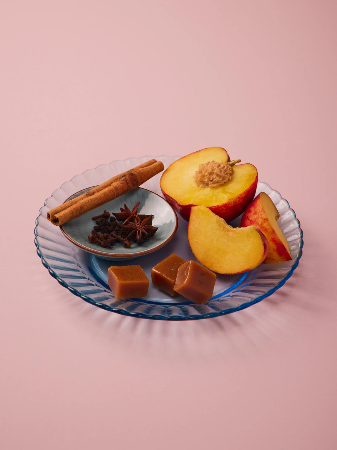 Blue glass plate with peach slices, cinnamon sticks, star anise and caramels