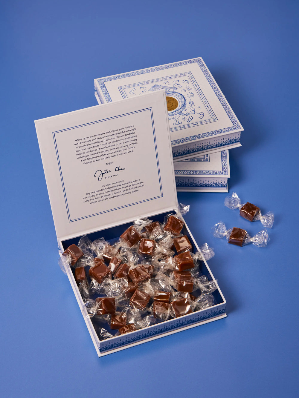 Open Le Bon Garcon gift box filled with individually wrapped caramels, on a blue background