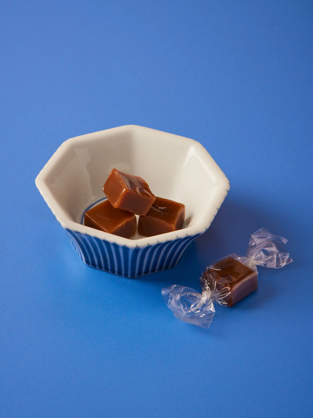 Earl Grey caramels in a blue and white bowl with wrapped caramels beside it