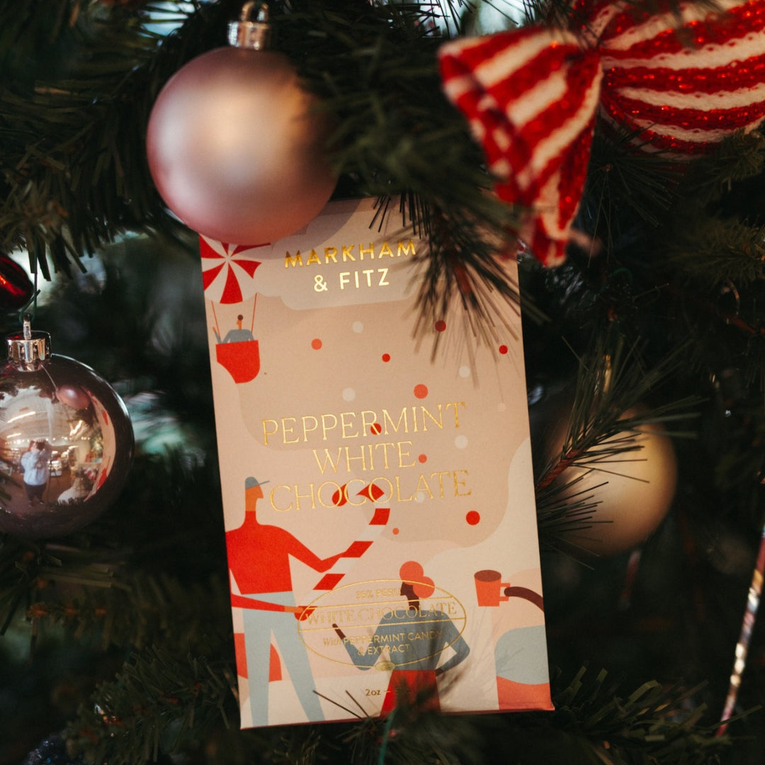Peppermint White Chocolate bar in its illustrated sleeve, tucked into a decorated Christmas tree