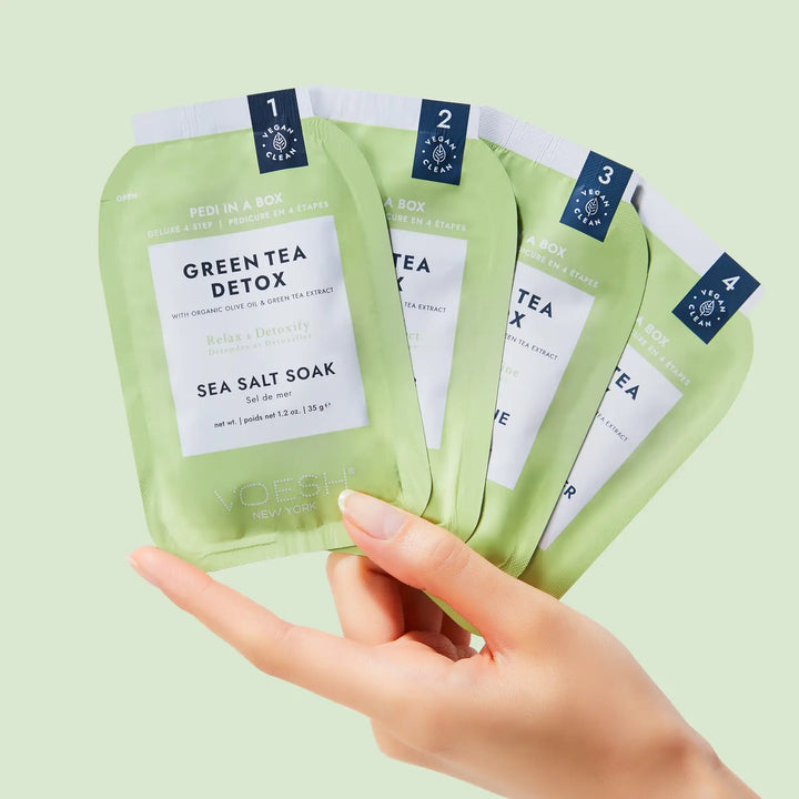 Hand holding the four numbered VOESH Pedi in a Box Green Tea Detox step packets