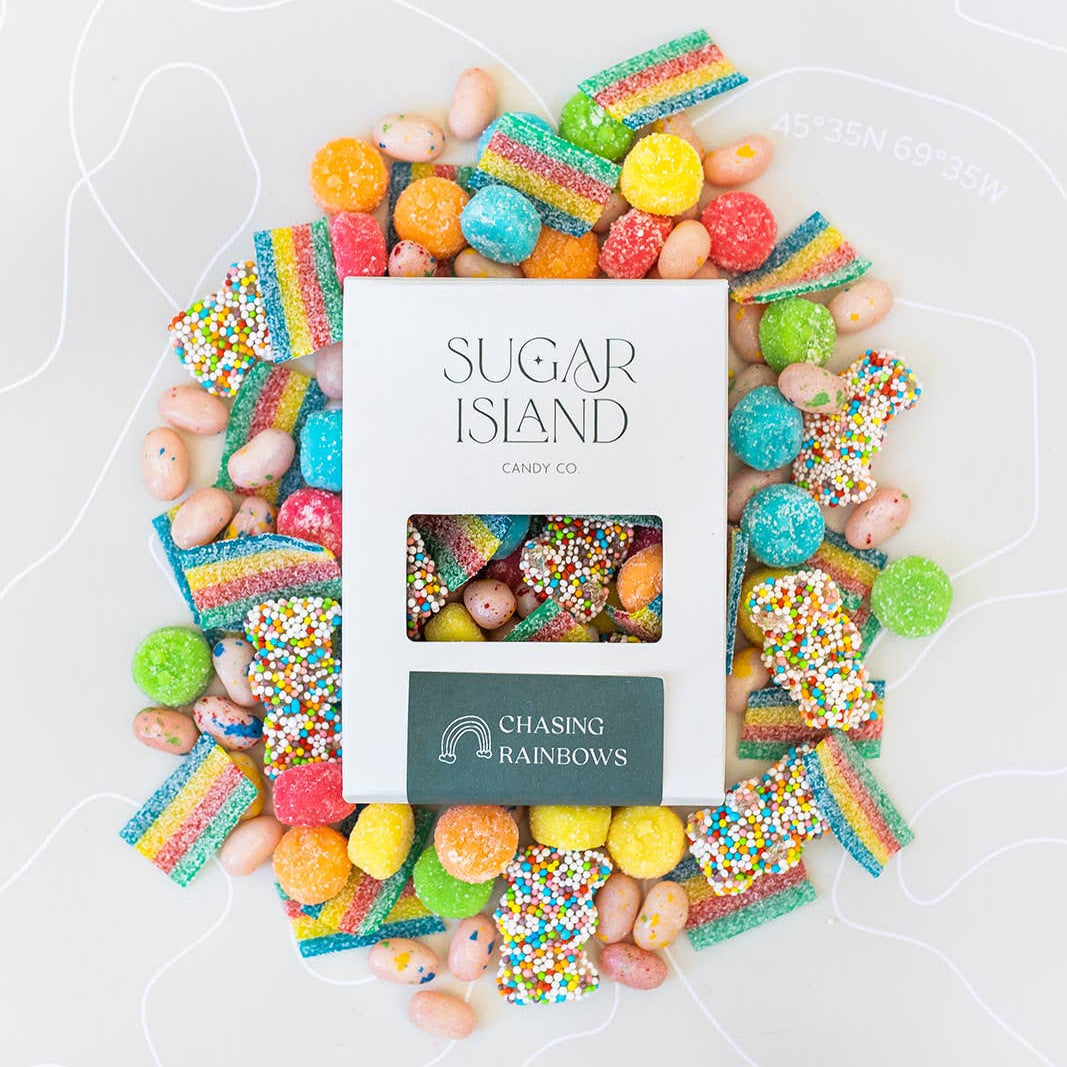 Chasing Rainbows box surrounded by rainbow sour strips, sprinkle-coated gummies and jelly beans