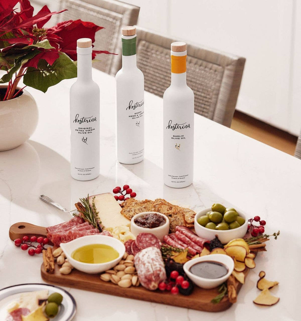 Three Kosterina olive oil bottles standing beside the open gift box