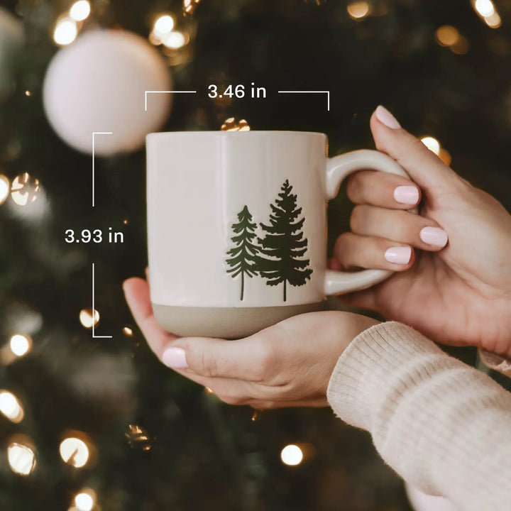 Hands holding the mug in front of a lit Christmas tree, labeled 3.46 inches across and 3.93 inches tall