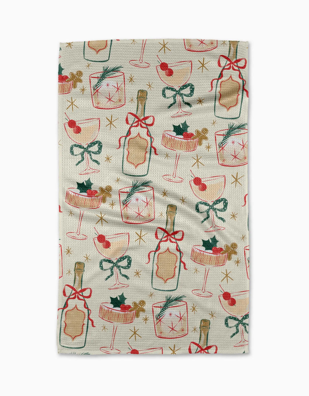 Cream waffle-weave tea towel laid flat, printed with a repeating holiday cocktail pattern in red, green, and gold: champagne bottles tied with ribbon, coupe and rocks glasses, gingerbread men, holly, and gold starbursts.