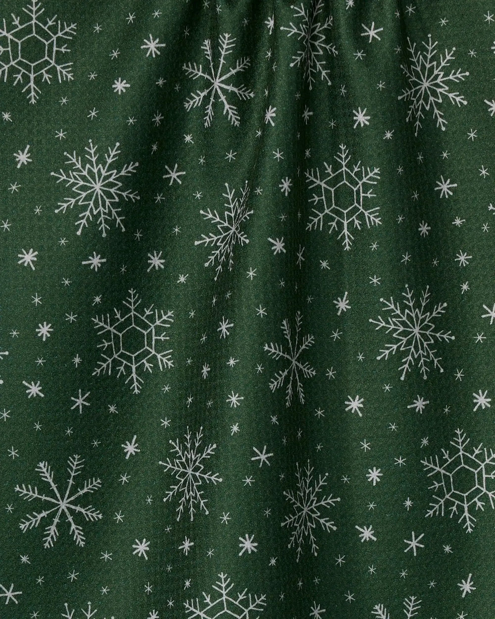 Close view of the Firlight tea towel's textured Geoweave fabric in forest green, with white snowflakes printed across it