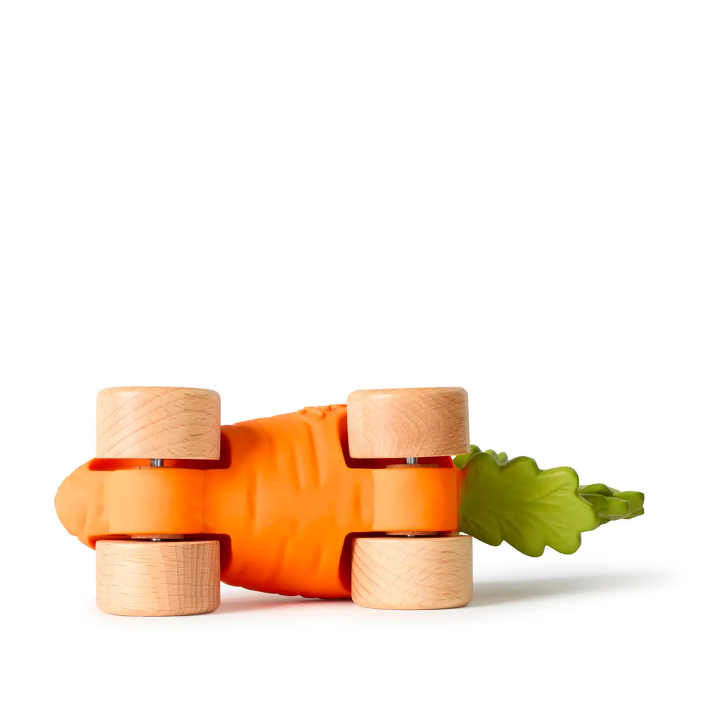 The carrot car tipped onto its side, showing the four natural wood wheels and metal axles.