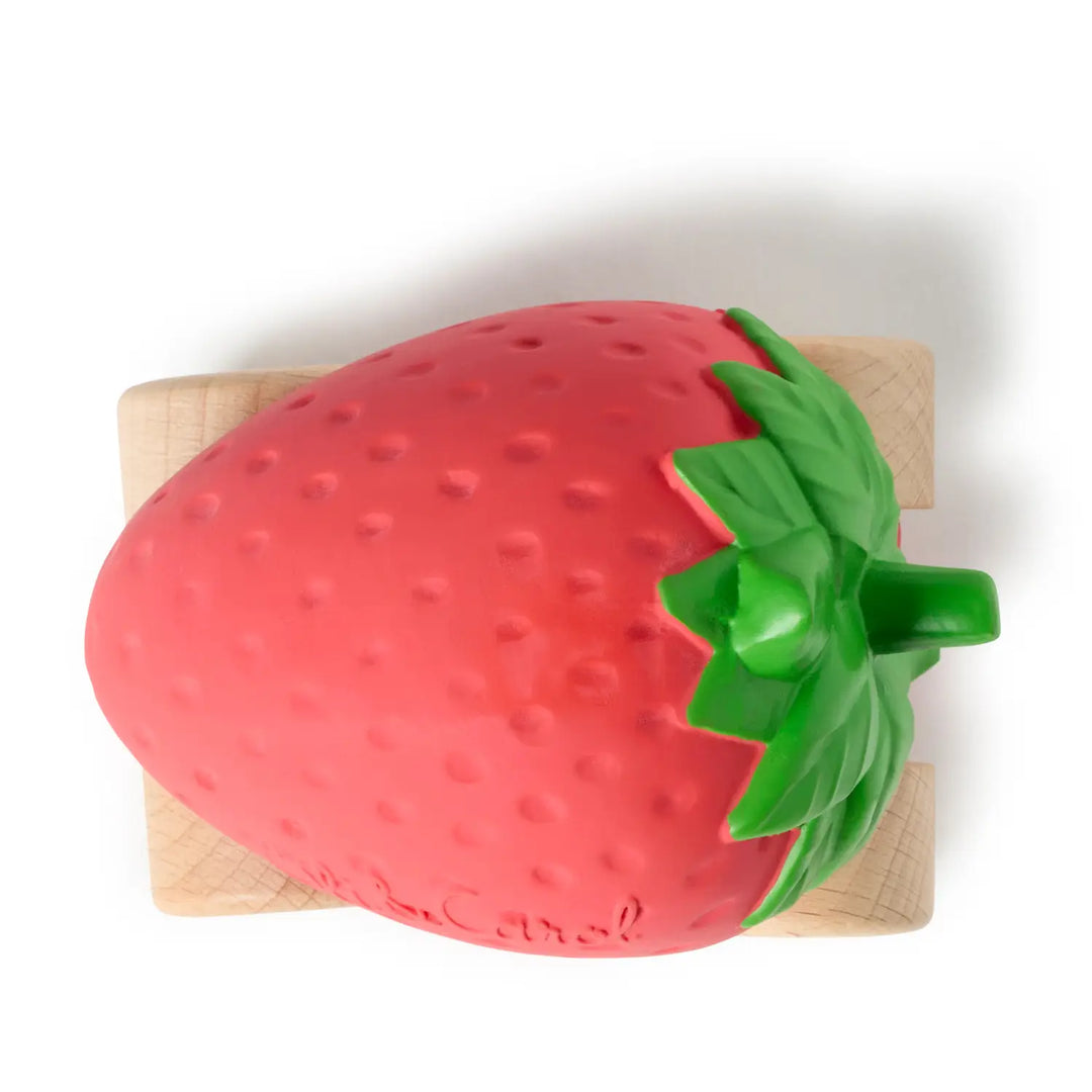 Overhead view of the red rubber strawberry body, showing its dimpled surface and green leaves.