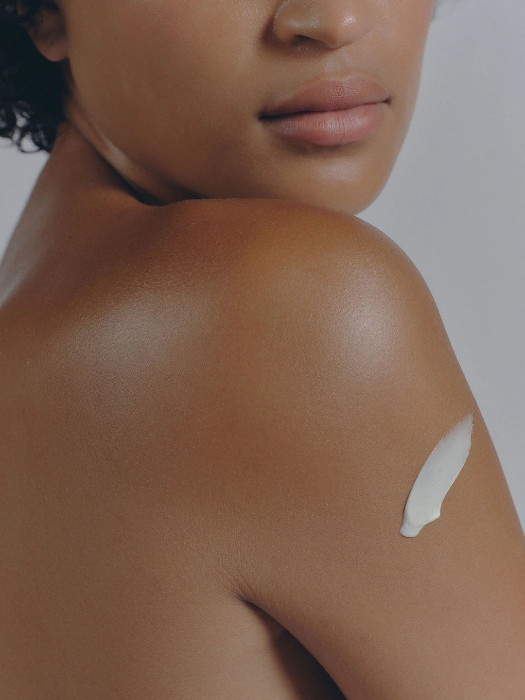 Close view of a bare shoulder with a white swatch of cream on the skin