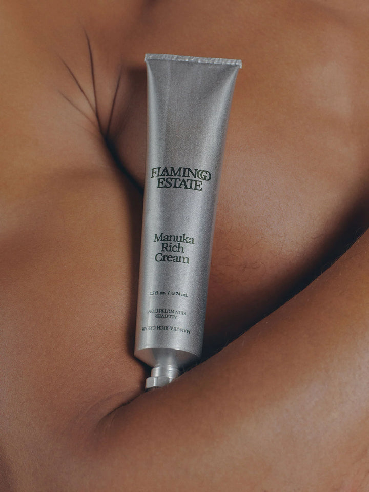Silver aluminum cream tube lying on bare skin, the Flamingo Estate label and 2.5 fl oz marking visible