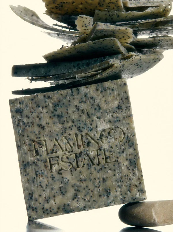 Close view of the soap brick upright with thin soap shavings curling above it, showing the poppy seed speckling