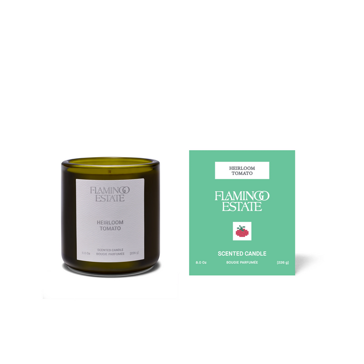 The olive-green Heirloom Tomato Candle beside its jade-green gift box, printed with a small tomato illustration and the Flamingo Estate name