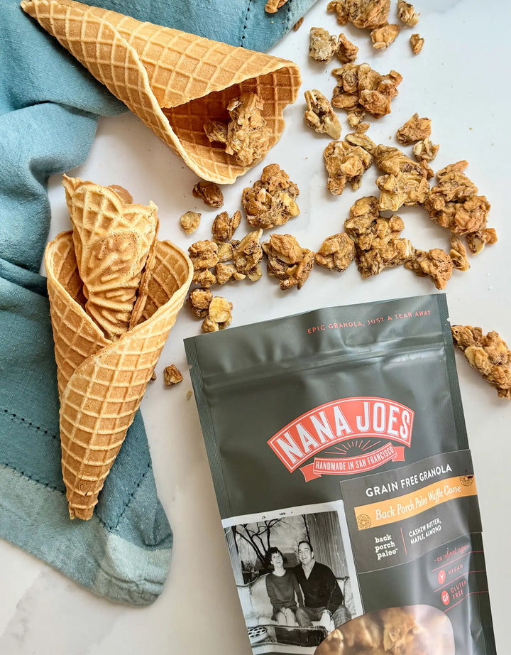 Waffle Cone Granola bag beside two waffle cones and scattered granola clusters on a blue linen cloth