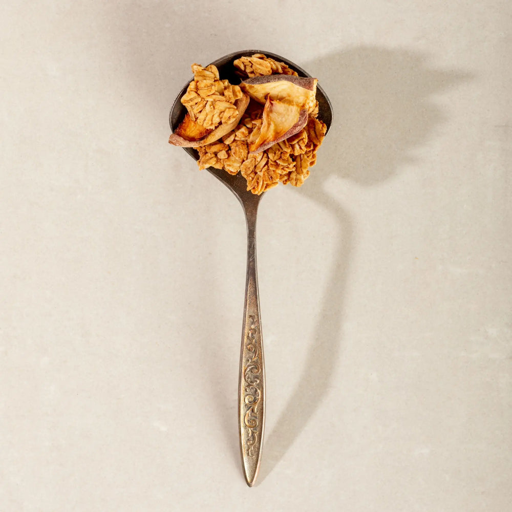 Vintage silver spoon holding granola clusters with dried peach pieces