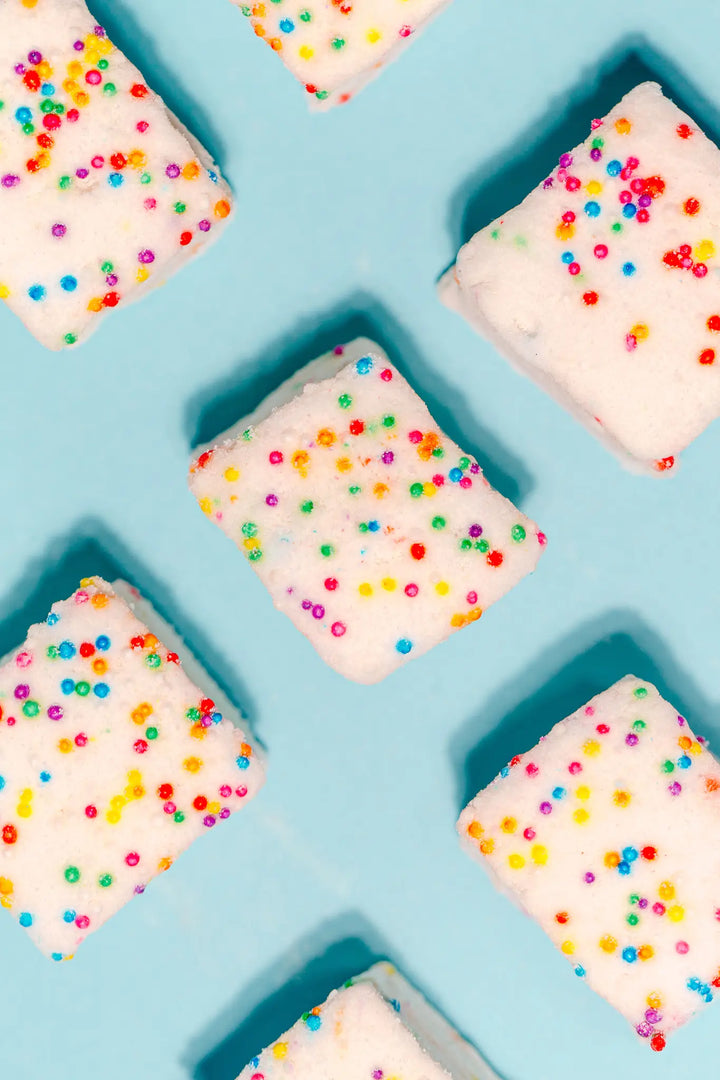 Rows of sprinkle-covered marshmallow squares on a light blue background