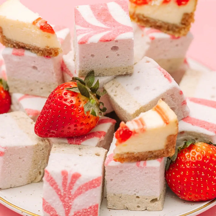 Plate piled with swirled marshmallows, cheesecake pieces and strawberries