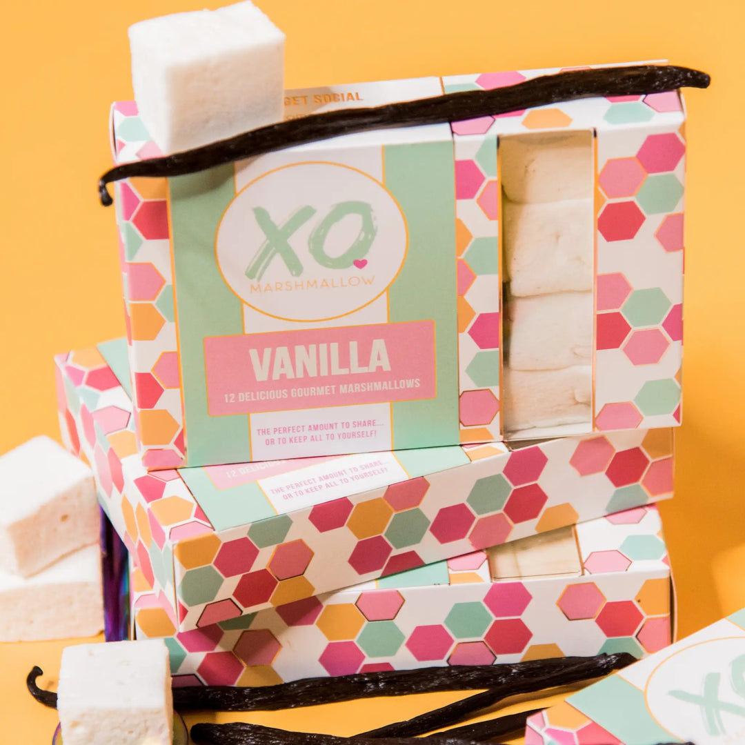 Stacked XO Vanilla marshmallow boxes with a vanilla pod and marshmallow cubes