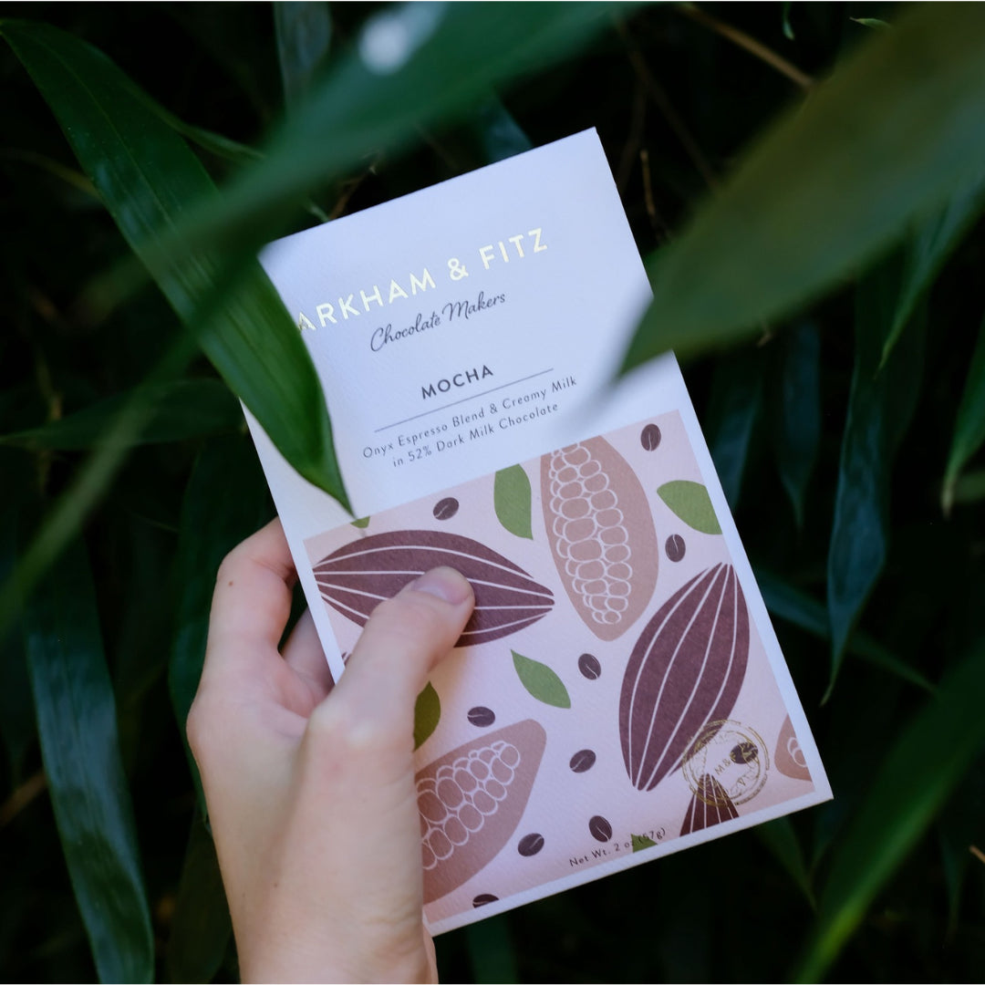 Hand holding the Mocha bar upright against dark green foliage