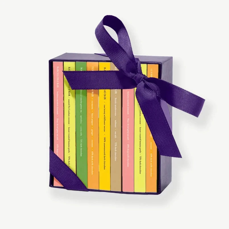 Ribbon-tied purple box holding eight mini chocolate bars in colorful wrappers