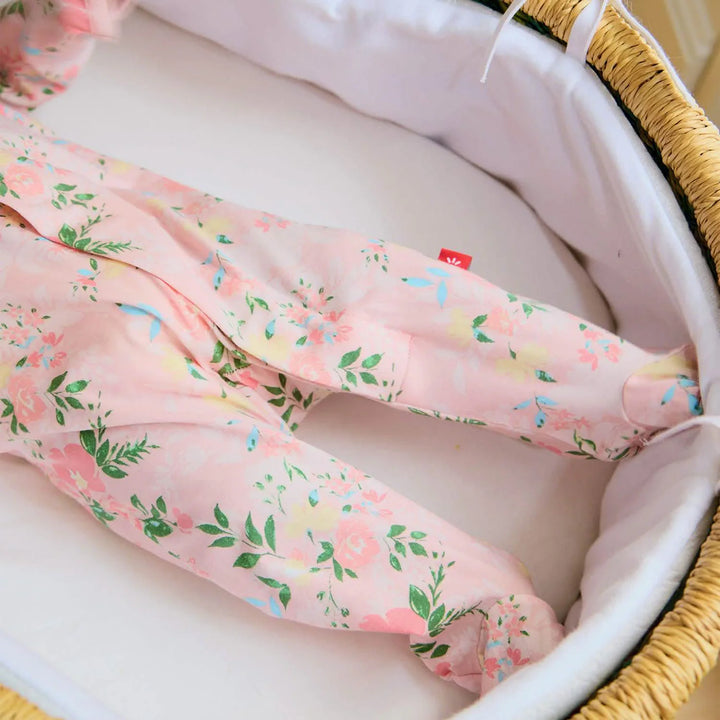 Pink floral baby footie pajamas in a woven Moses basket with white lining