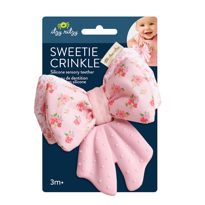 Pink floral bow baby teether with textured silicone, displayed on branded blue packaging