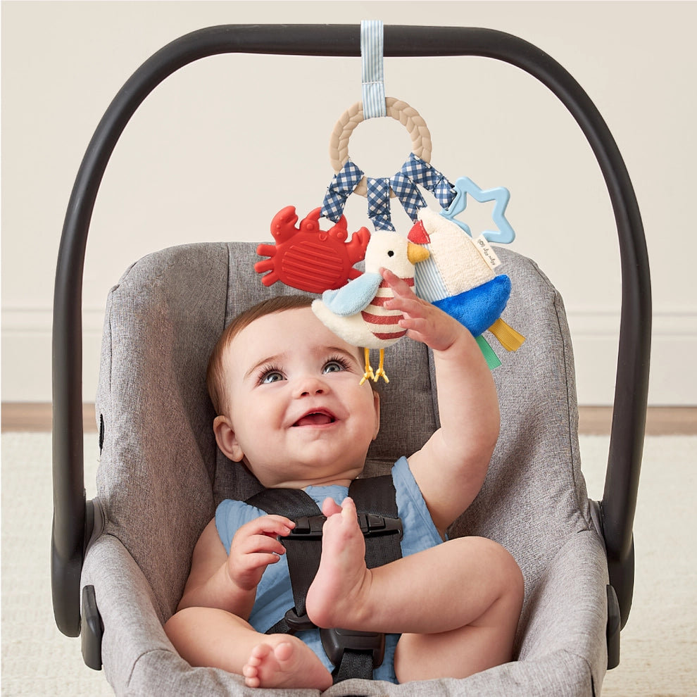 Baby in car seat reaching for nautical-themed activity toy with plush sea animals